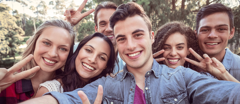 Eine Gruppe Jugendlicher macht ein Selfie und lächelt dabei in die Kamera.