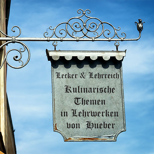 Ein eisernes Gasthausschild mit der Aufschrift:Lecker & lehrreich: Kulinarische Themen in Hueber-Lehrwerken